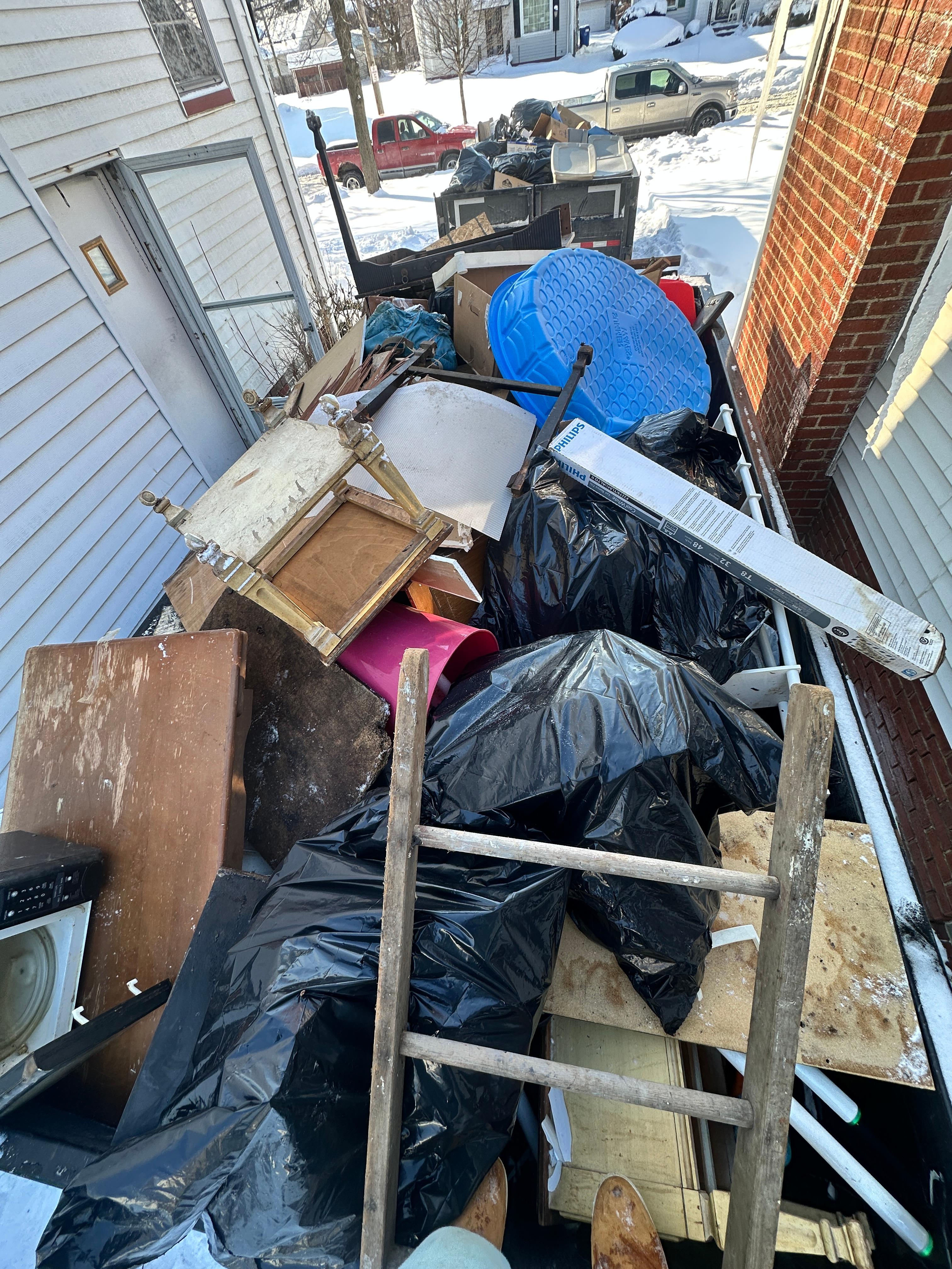 Heavy porch cleanout with bagged debris and furniture ready for removal